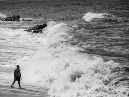 Bather on the beach during a heavy storm. Waves that crash powerfully on the shore.の写真素材