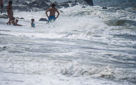 Bathers on the beach during a heavy storm. Waves that crash powerfully on the shore.の写真素材