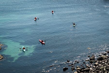 A group of kayakers on top of a blue ocean making their way up the coastの写真素材