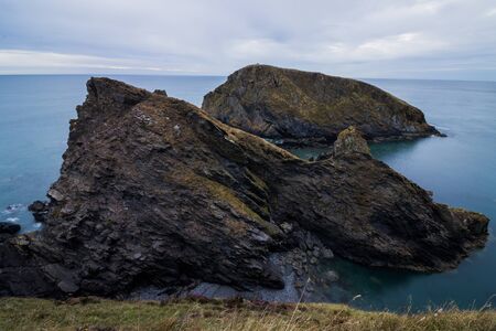 Some large coastal rock formations surrounded by a deep blue seaの写真素材