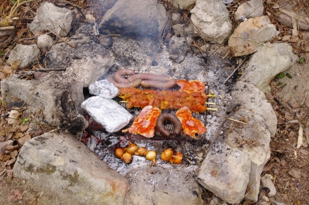 Sausages, steak and pork spit cooking on a grill の写真素材