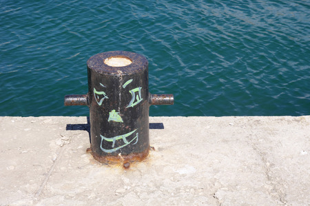 Painted black bollard with smiling face in sunny day