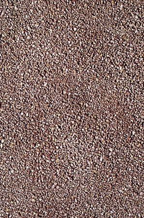 Red pebble mosaic pebbles wall closeup in sunny day