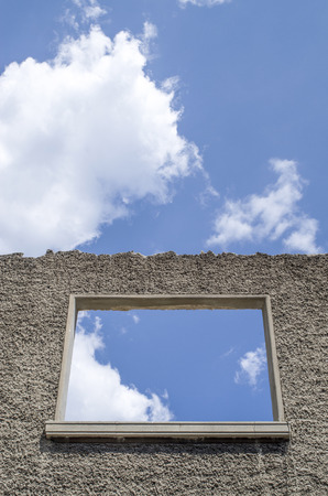 Old wall of ruin of house and window against sky with cloudsの写真素材