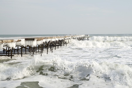 Old icy pier with icicles  in winter in stormy sea      
の写真素材