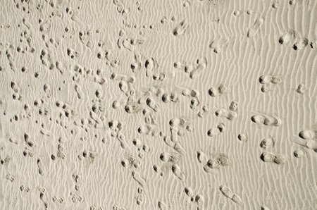 Human footprints in dry sand closeup in sunny day