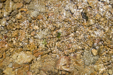 Pebbles in creek or stream flowing water closeup
