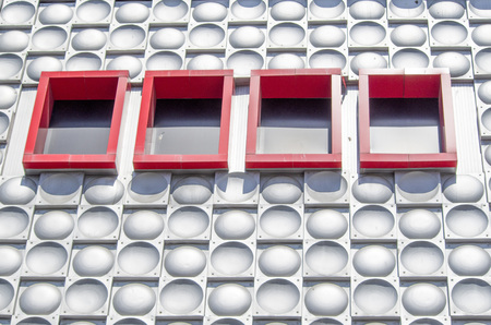 Retro decorative metal hemisphere elements on a wall and red windows