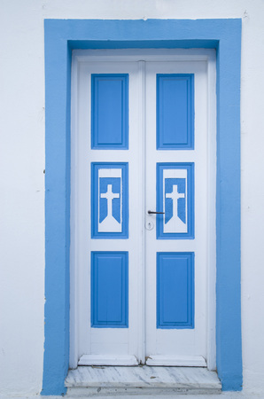 Old blue wooden church door on white wall, Santorini, Greeceの写真素材