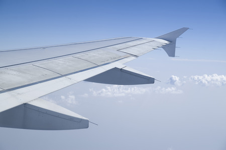 Airplane wing in the  cloudy blue sky