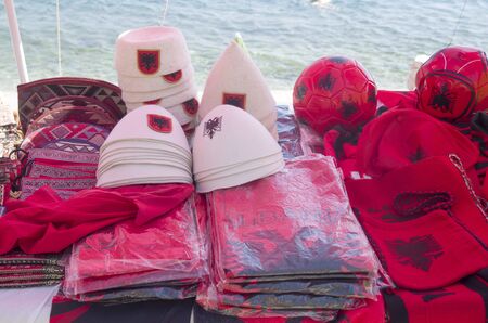 Albanian souvenirs - traditional hats and red t-shirts with a black double-headed eagle coat of armsの写真素材