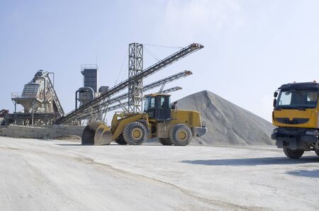 Wheel medium-sized Loader and several belt conveyors and piles of rubble in Gravel Quarry