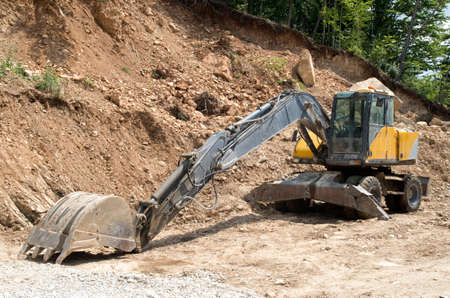 Medium wheel excavator with bucket in sunny day