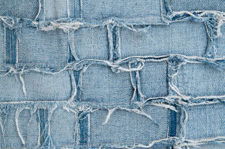 Surface of pieces of old tattered denim closeup