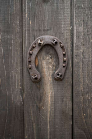 Old rusty horseshoe nailed to a front wooden door closeupの写真素材