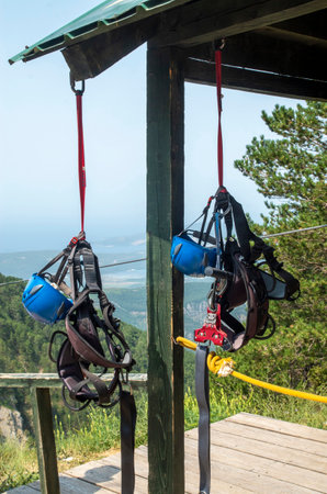 Two hanging trolley gear: seat, helmet and pulley in mountainの写真素材