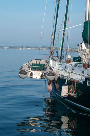 Sailboat with hanging inflatable lifeboat in harbor in morning