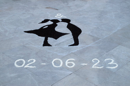 Wedding drawing of girl and boy kissing painted with black and white rice on ground in front of a church in Italyの写真素材