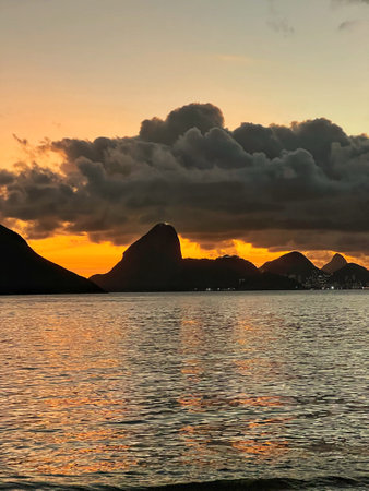 Sunset by the sea with a view of the mountains. Orange sky with clouds
