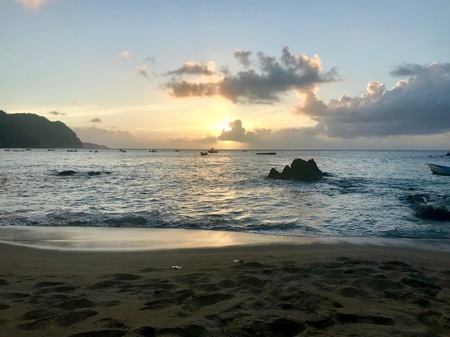 Beautiful Caribbean Tobago Sunset (Trinidad and Tobago, West Indies): orange sky, clouds, sand beach and wavy oceanの写真素材