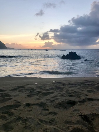 Beautiful Caribbean Tobago Sunset (Trinidad and Tobago, West Indies): orange sky, clouds, sand beach and wavy oceanの写真素材