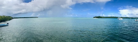 Beautiful view of the Caribbean island of Tobago (Trinidad - West Indies) from a boat: sand beach, palm tree, turquoise water and blue sky with white cloudsの写真素材