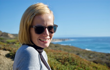 Happy blonde woman enjoying the beautiful coastal view in California (USA): Pacific ocean with limestone rock cliffs and a clear blue summer sky without cloudsの写真素材