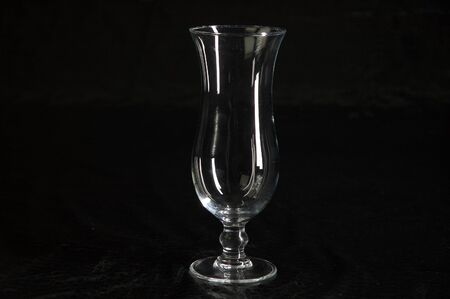 Still life with one single modern transparent and fragile glass on a table with a black backgroundの写真素材