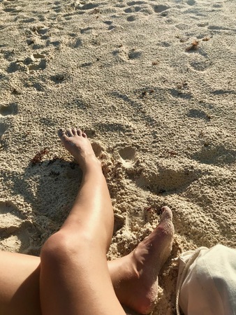 Legs of a caucasian tourist enjoying a beautiful day on the sand beach of the Caribbean island of Barbados in the West Indiesの写真素材