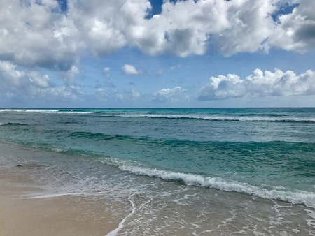 Idyllic and beautiful beach in Barbados: Nobody, white sand, turquoise water, waves and white cloudsの写真素材
