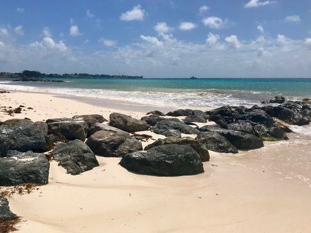 Idyllic scenic view Which beach in Oistins, Barbados (Caribbean island of the West Indies) with large black stones, white sand and a turquoise ocean on a beautiful day with a clear blue skyの写真素材