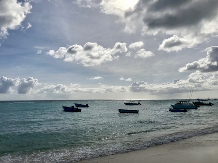 Scenic panoramic view of a beautiful sand beach in Barbados (Caribbean Island of the West Indies) with blue sky, white clouds and fishing boats out in the turquoise colored oceanの写真素材