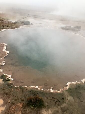 The Konungshver geyser, part of Haukadalur, the geothermal and geothermal features along the Golden Circle tourist route in Southern Iceland on a foggy autumn afternoonの写真素材