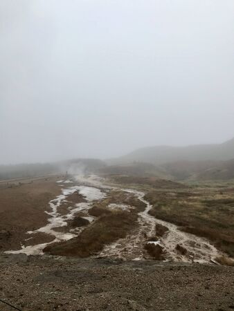 Scenic autumn / winter landscape with mud, bushes, fog, boiling water and ice around geothermal area of The Great Geysir in Iceland: natural landmark of the Golden Circleの写真素材