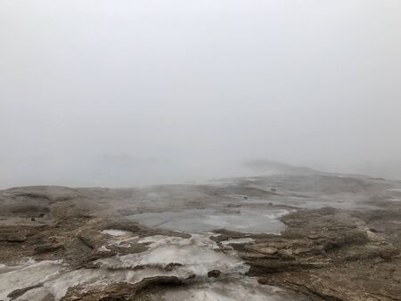 Scenic autumn / winter landscape with mud, bushes, fog, boiling water and ice around geothermal area of The Great Geysir in Iceland: natural landmark of the Golden Circleの写真素材