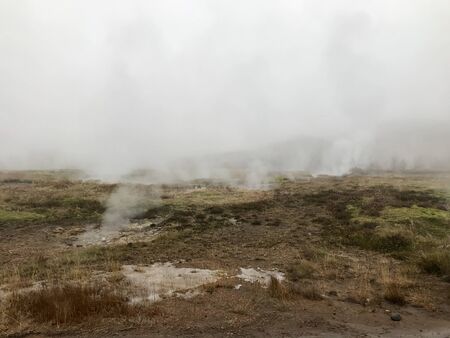 Nordic landscape in Haukadalur valley (Iceland) on a cold autumn / winter day in the geothermal area of The Great Geysir: mud roads, rocks & volcanic nature releasing hot water through geyser springsの写真素材
