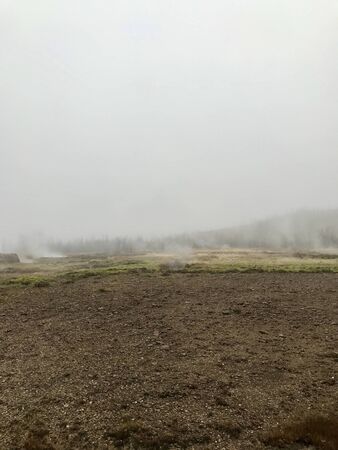 Nordic landscape in Haukadalur valley (Iceland) on a cold autumn / winter day in the geothermal area of The Great Geysir: mud roads, rocks & volcanic nature releasing hot water through geyser springsの写真素材