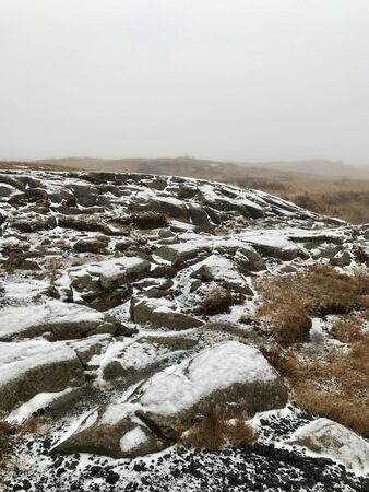 Adventure hike to the scenic landmark of the Gullfoss Waterfall on the Golden Circle Route in Iceland: beautiful nordic autumn / winter landscape with snow covered rocks, bushes and a foggy skyの写真素材