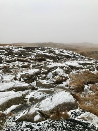 Adventure hike to the scenic landmark of the Gullfoss Waterfall on the Golden Circle Route in Iceland: beautiful nordic autumn / winter landscape with snow covered rocks, bushes and a foggy skyの写真素材