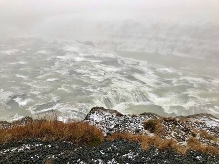 The majestic arctic Gullfoss waterfall landscape located in the canyon of the Hv?t? river on the Golden Circle Route in Iceland on a foggy autumn / winter day: Scenic cascades & cliffs with iceの写真素材