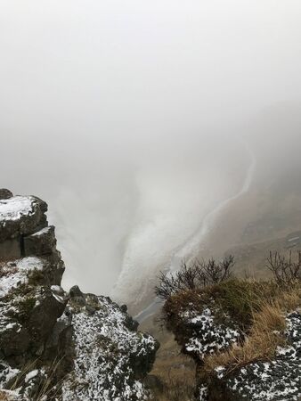 End of the world feeling at the cliffs of the Gullfoss Waterfall in Iceland: Frosted foggy winter landscape with rocks, cascades in the background and snow covered icelandic scenery in Novemberの写真素材