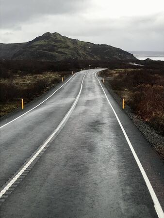 Tourism road trip journey along the Golden Circle from Reykjavik in Iceland (Europe): Scenic wilderness view & countryside with empty autumn road & clouds in the skyの写真素材