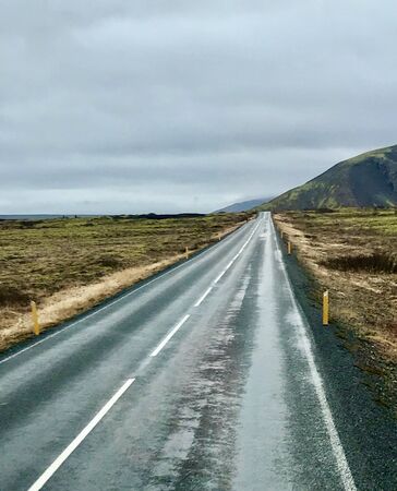 Tourism road trip journey along the Golden Circle from Reykjavik in Iceland (Europe): Scenic wilderness view & countryside with empty autumn road & clouds in the skyの写真素材