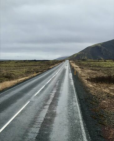 Tourism road trip journey along the Golden Circle from Reykjavik in Iceland (Europe): Scenic wilderness view & countryside with empty autumn road & clouds in the skyの写真素材