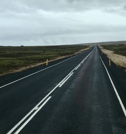 Tourism road trip journey along the Golden Circle from Reykjavik in Iceland (Europe): Scenic wilderness view & countryside with empty autumn road & clouds in the skyの写真素材