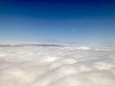 Beautiful heavens gate high above the clouds: Idyllic aerial view from a airplane window with a lovely light blue sky & fluffy white clouds in the atmosphere gives a feeling of freedomの写真素材
