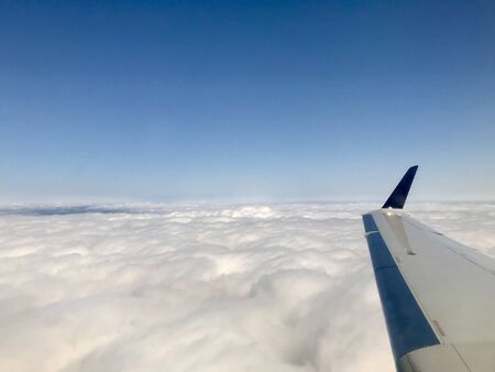 Beautiful heavens gate high above the clouds: Idyllic aerial view from a airplane window with a lovely light blue sky & fluffy white clouds in the atmosphere gives a feeling of freedomの写真素材