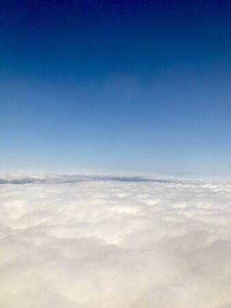 Beautiful heavens gate high above the clouds: Idyllic aerial view from a airplane window with a lovely light blue sky & fluffy white clouds in the atmosphere gives a feeling of freedomの写真素材