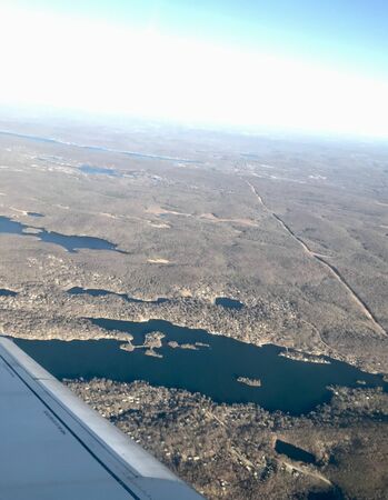 Beautiful birds eye view scene from air travel: Tranquil scenery of the airplane flying high above idyllic landscapes with its long wingの写真素材