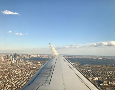 Airplane travel to EWR, Newark (NJ) in America: Horizontal aerial view from above the famous urban NYC metropolis / Manhattan skyline with highrise downtown buildings & the hudson in the backgroundの写真素材